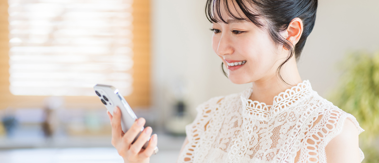 スマホを笑顔で見つめる女性