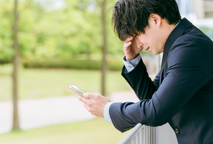 スマホを見て悩む男性